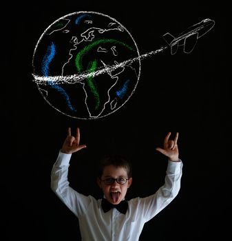 Knowledge rocks boy dressed up as business man with chalk globe and jet world travel on blackboard background