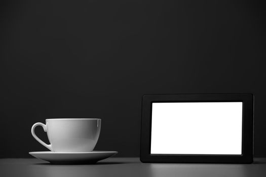 White mug and tablet computer on a gray background.