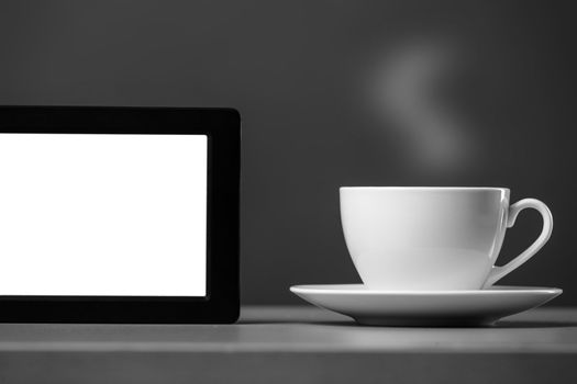 White mug and tablet computer on a gray background.