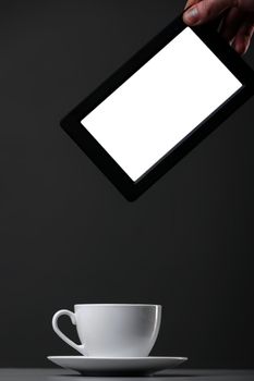 White mug and tablet computer on a gray background.