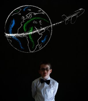Thinking boy dressed up as business man with chalk globe and jet world travel on blackboard background