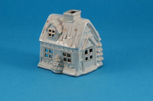 small white ceramic toy christmas house decoration on blue background.