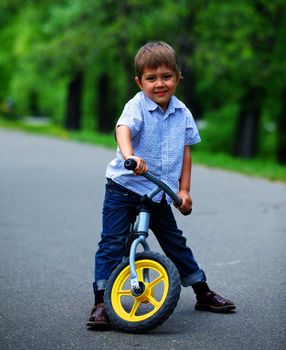 Little boy on a bicycle and his mother in the summer park