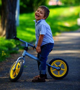 Little boy on a bicycle and his mother in the summer park