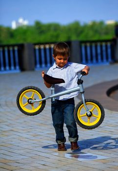 Little boy on a bicycle and his mother in the summer park