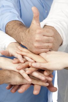 Diverse group of people with their hands together with a thumb up on top 