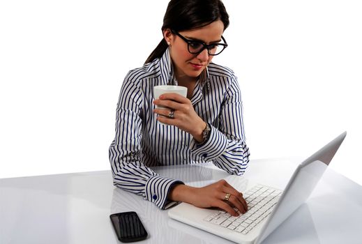 Young executive woman with glasses working on laptop computer and holding a cup of coffee, over a white backgroud