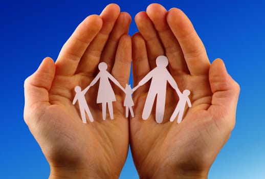 Paper family in hands isolated on blue sky
