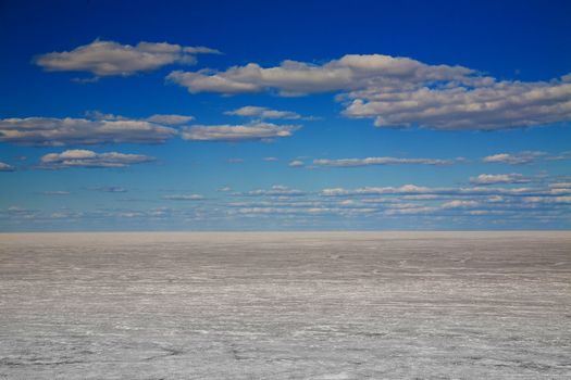 Frozen lake and blue sky with clouds. Winter landscape.