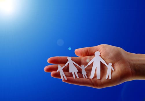 Paper family in hands isolated on blue sky