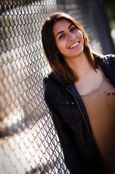 Beautiful Mixed Race Young Woman Portrait Outside Against Chain Link Fence.