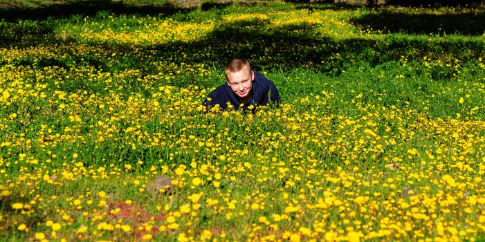 Attractive resting kid lay on the fresh spring meadow