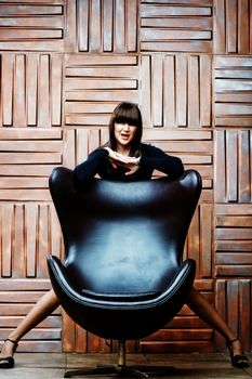 Girl model posing for a leather armchair.