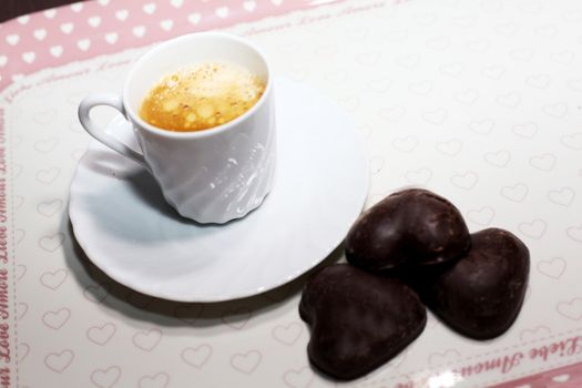 A cup of coffee on a tray with some chocolate..