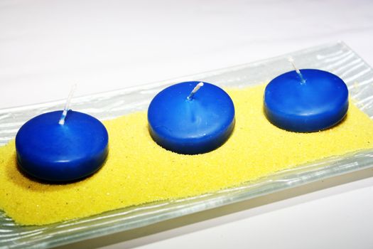 three blue candles on yellow sand