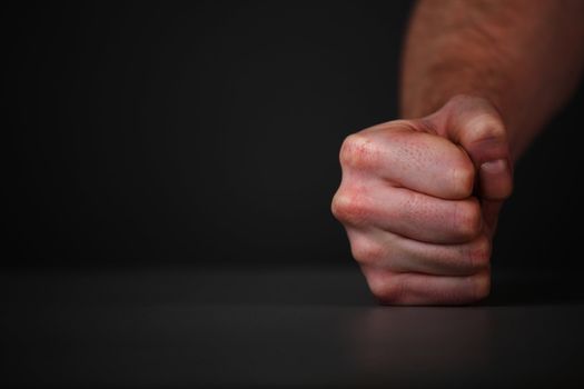 Male fist on the table. On gray background