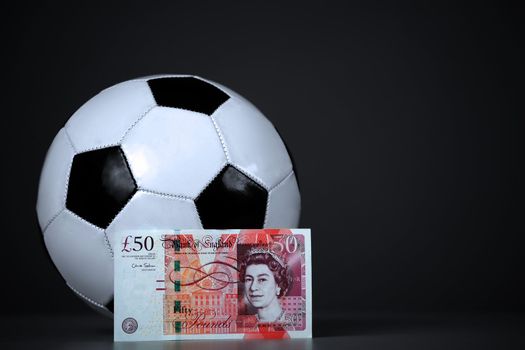 Fifty pounds sterling and soccer ball. On a gray background