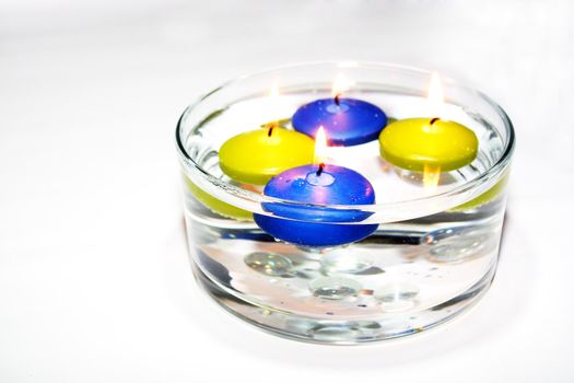 Colored folating candles on water with water drops