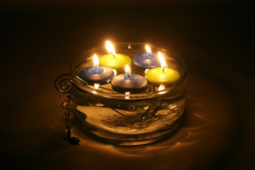 Colored folating candles on water with water drops