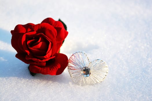 beautiful red rose in snow with crystal heart in a winter day