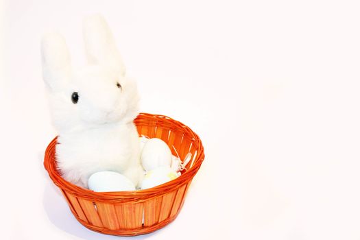 Cute white eastern bunny in a basket with eastern eggs