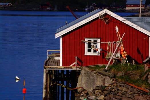 Picturesque red fishing hut on the coast of fjord on Lofoten islands in Norway