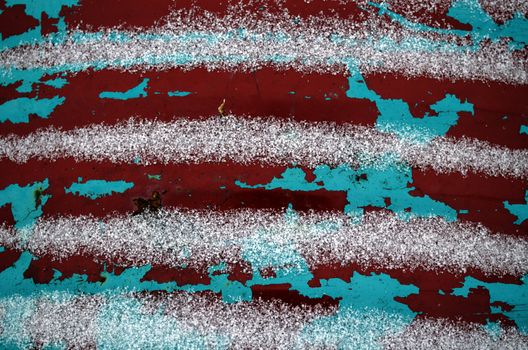 old peeled paint rusty barrel wall covered with snow in winter background.