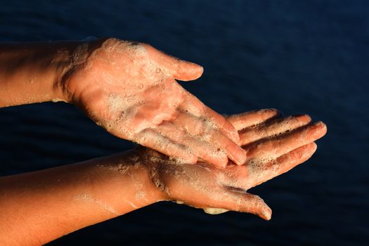 Women's hands in the foam on the background of sea water