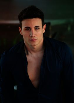 Attractive and trendy young man standing with shirt open showing torso 