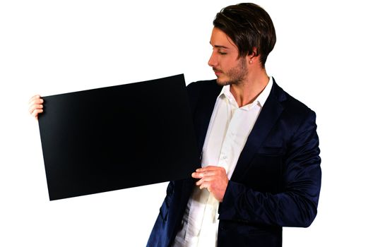 Attractive young man holding and showing empty, blank black board, sign or paper sheet