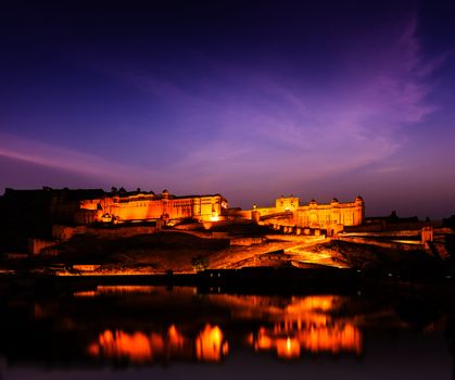 Amer Fort (Amber Fort) illuminated at night - one of principal attractions in Jaipur, Rajastan, India refelcting in Maota lake in twilight