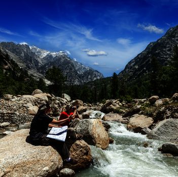 Hiker trekkers read a trekking map on trek in Himalayas mountains. Himachal Pradesh,India