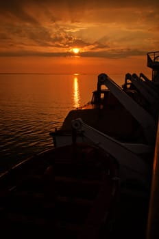 Sunset wtih lifeboats on a ship in the foreground