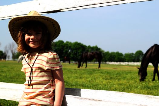 little girl with cowboy hat on farm