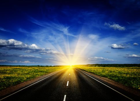 Travel concept background - road in blooming spring meadow on sunset