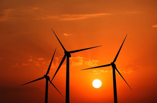 Green renewable energy concept - wind generator turbines in sky on sunset