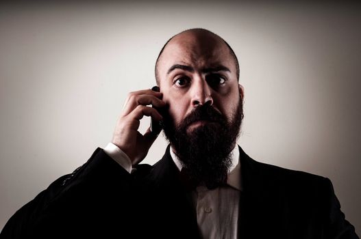  funny elegant bearded man on the phone on vignetting background