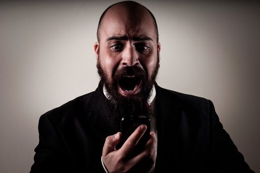  funny elegant bearded man screaming on the phone on vignetting background