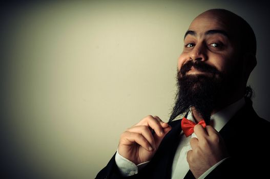  funny elegant bearded man touching beard on vignetting background