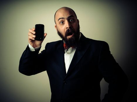  funny elegant bearded man showing phone on vignetting background