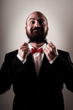 funny elegant bearded man touching beard on vignetting background