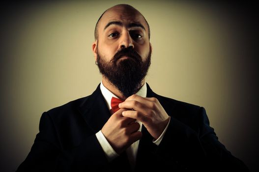  funny elegant bearded man touching beard on vignetting background