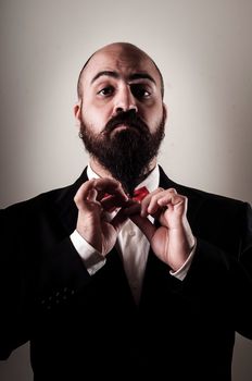  funny elegant bearded man touching beard on vignetting background