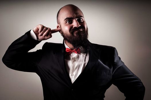  funny elegant bearded man with finger in the ear on vignetting background