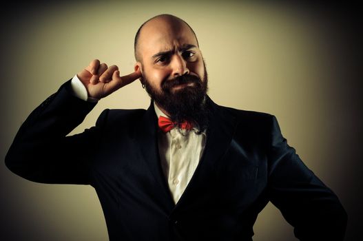  funny elegant bearded man with finger in the ear on vignetting background