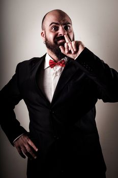  funny elegant bearded man with finger in the nose on vignetting background