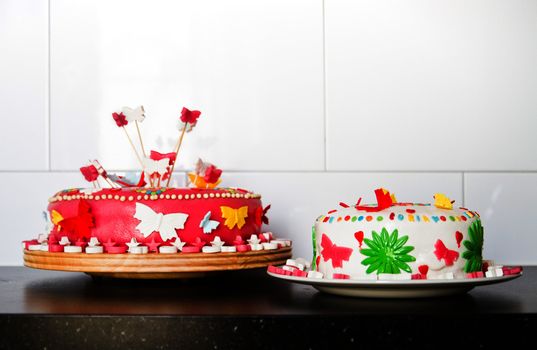 Colorful decorated white and pink Marzipan cakes for a birthday party on kitchen dresser