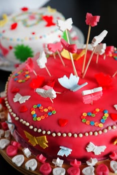 Colorful decorated white and pink Marzipan cakes for a birthday party on kitchen dresser - close up with shallow dof