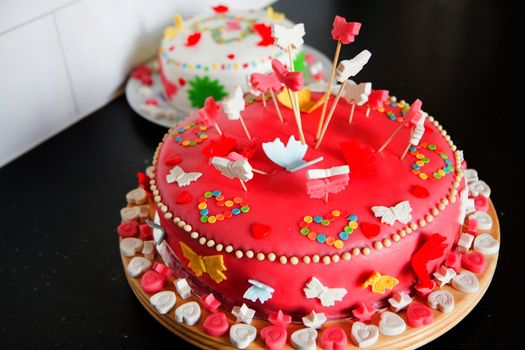 Colorful decorated white and pink Marzipan cakes for a birthday party on kitchen dresser 