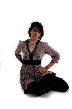 young brunette woman in dress sitting on the ground with boots